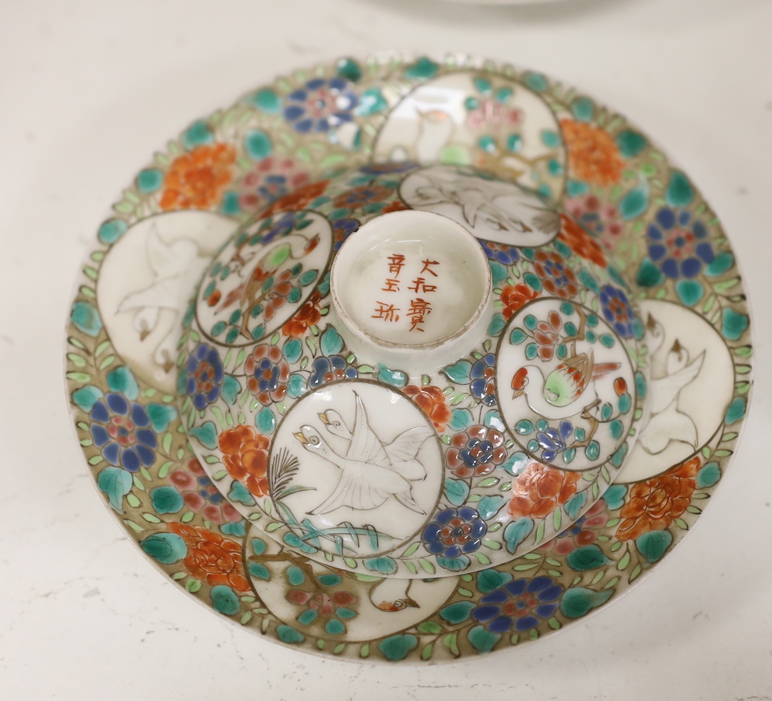 Two Japanese tea bowls one with cover and saucer, a saucer and cover, two Chinese soapstone carvings and four stands